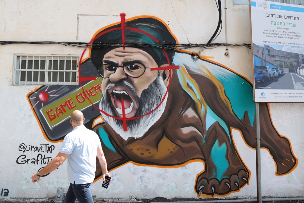 A man walks past a mural in Tel Aviv showing slain Hezbollah leader Hassan Nasrallah EPA-EFE/ABIR SULTAN